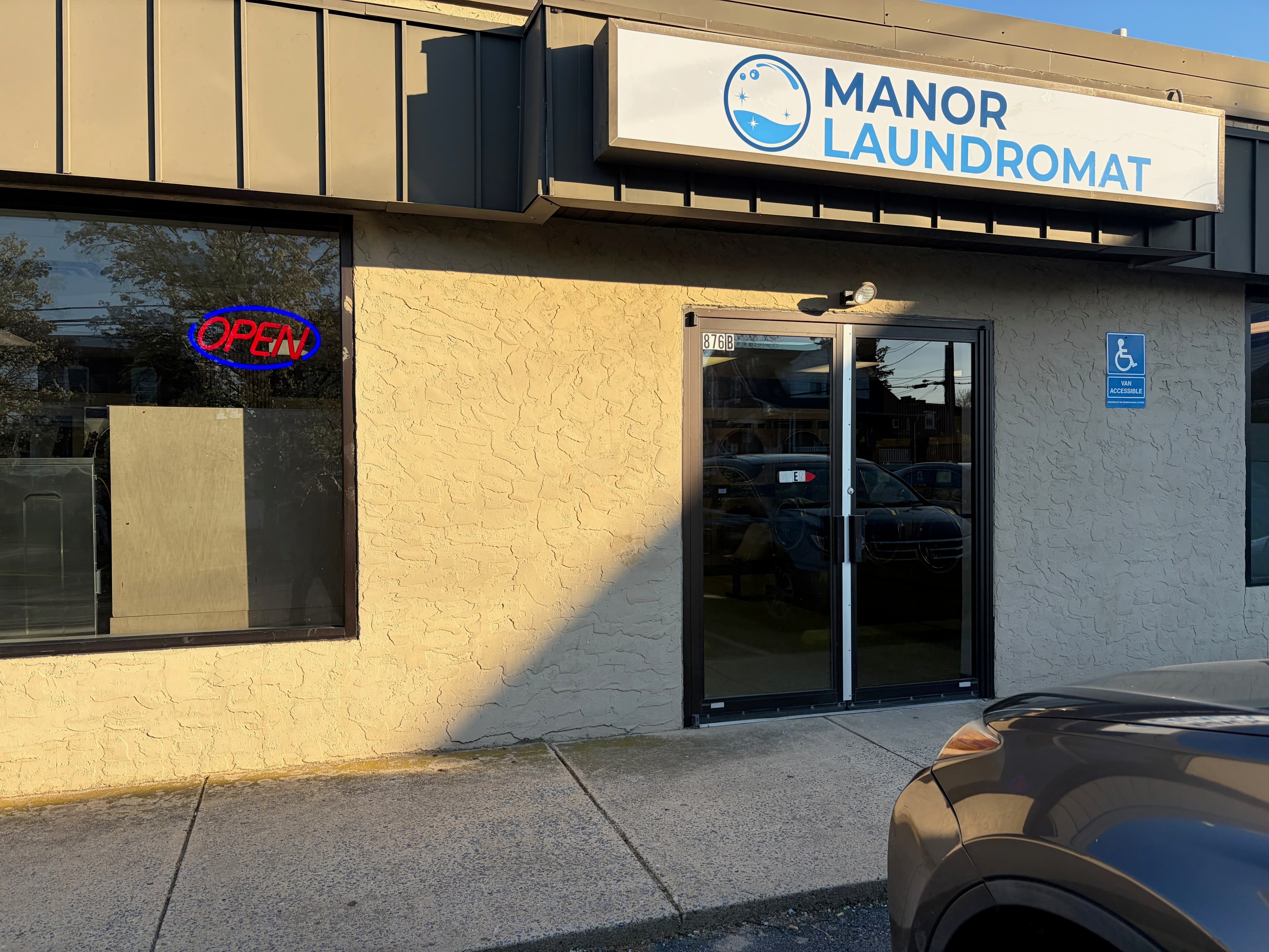 Exterior storefront of Manor Laundromat at 876 Manor Street, Lancaster PA, with open sign and parking